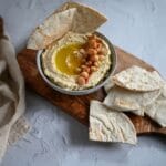 Domowy hummus z pitą na drewnianej desce jako zdrowa przekąska