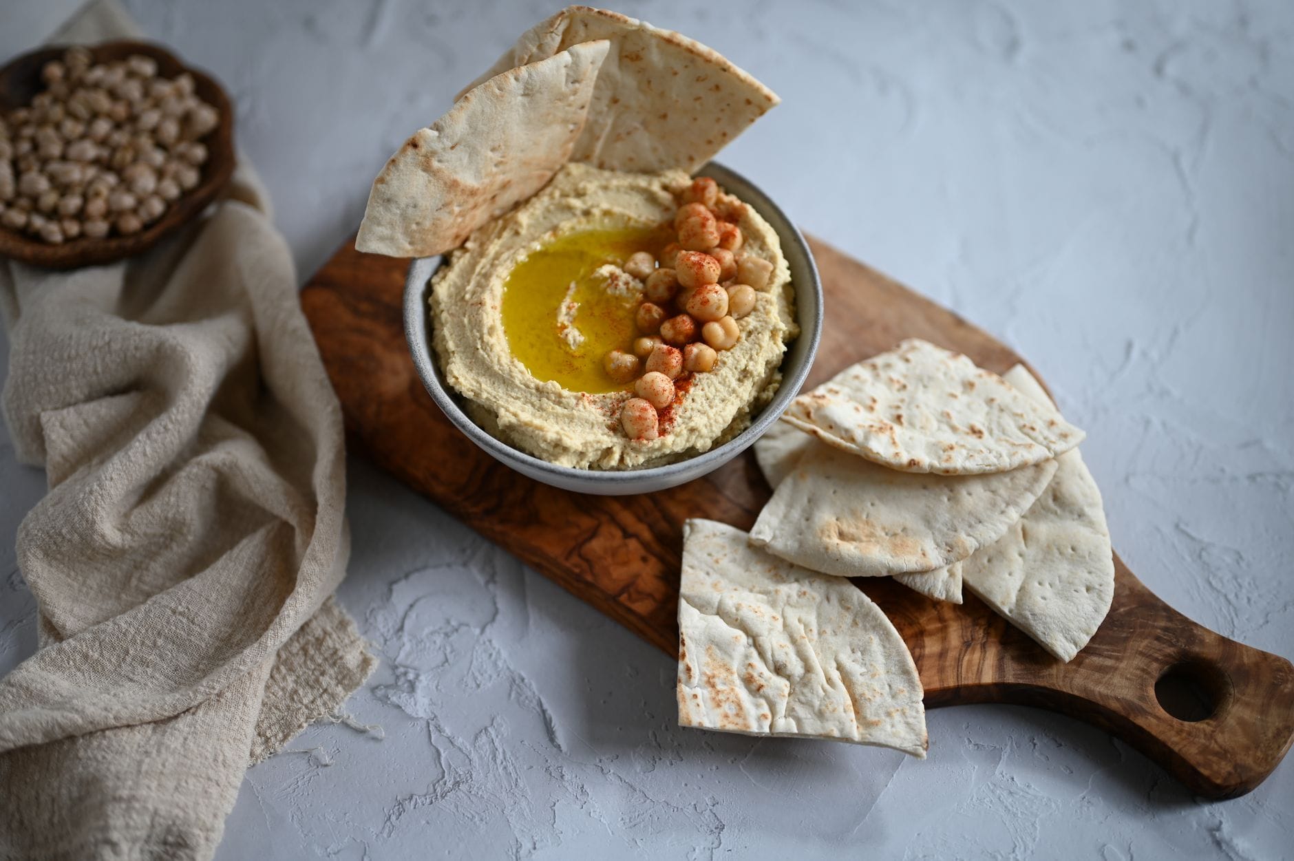 Domowy hummus z pitą na drewnianej desce jako zdrowa przekąska