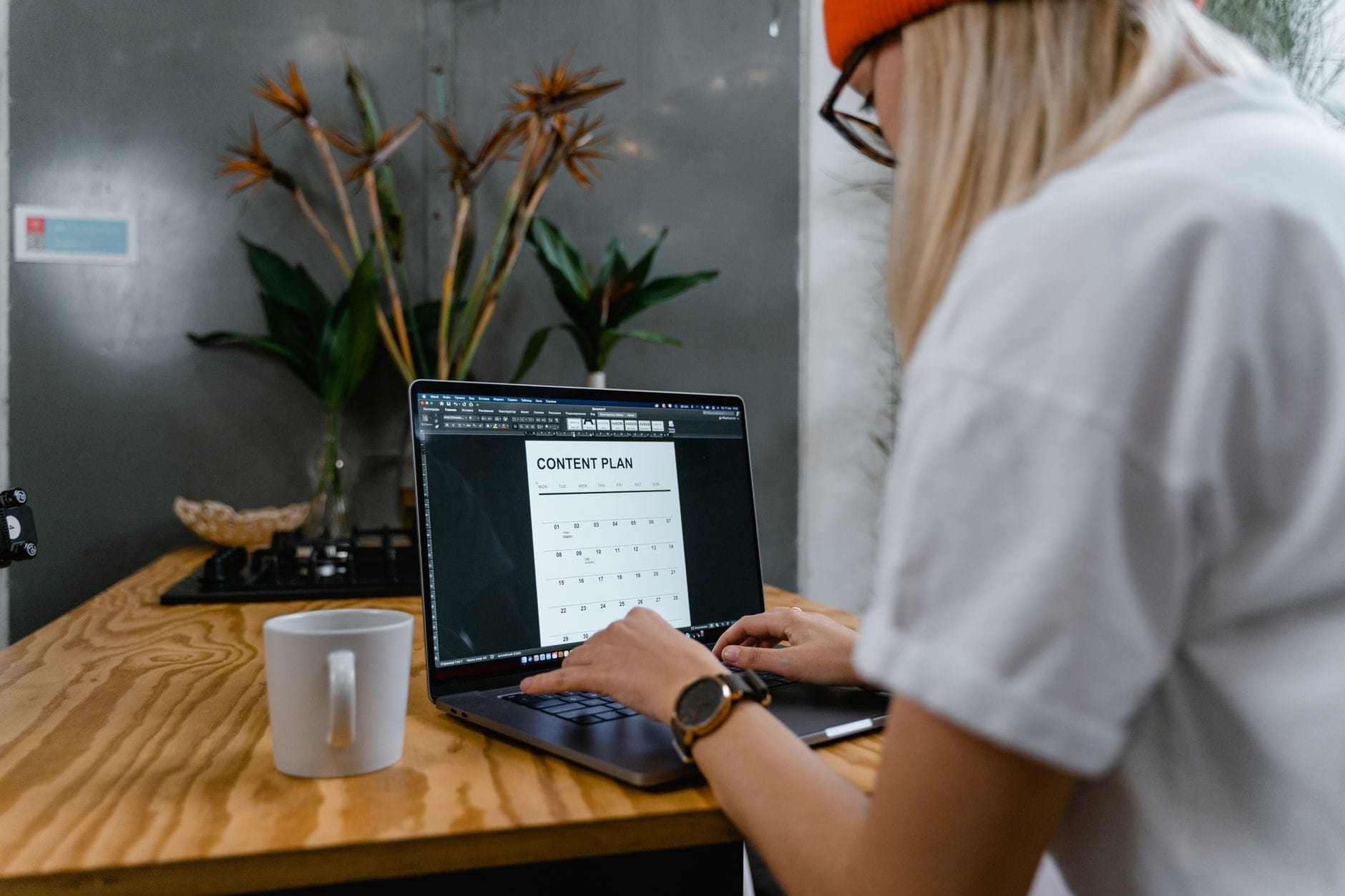 Kobieta skupiona przy laptopie planuje treści na blog w nowoczesnym biurze
