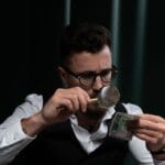 Mężczyzna w pomieszczeniu sprawdza banknot lupą
