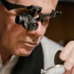 Zegarmistrz z lupą dokładnie ogląda mechanizm kieszonkowego zegarka